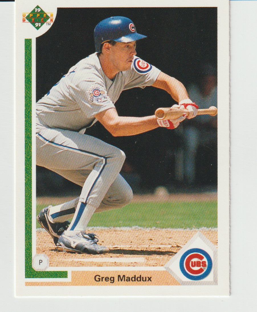 Baseball trading card of Greg Maddux in a Cubs uniform, holding a bat.