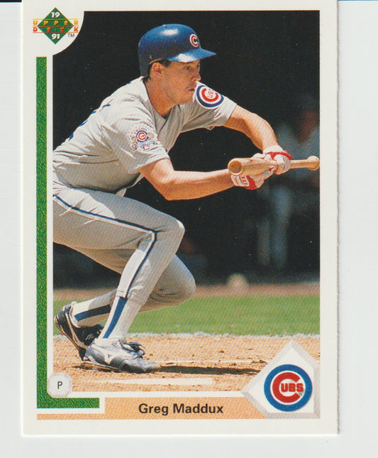 Baseball trading card of Greg Maddux in a Cubs uniform, holding a bat.