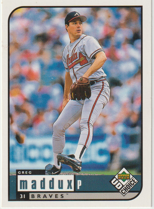 Baseball trading card of Greg Maddux in a Braves uniform with a blurred stadium background.