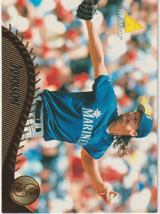 Baseball player in a blue uniform with 'Mariners' text, wearing a glove, against a blurred stadium background.